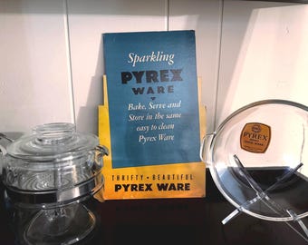 May include: An assortment of vintage Pyrex cookware and promotional materials. The image features a clear glass casserole dish, a glass pot with a metal stand, and a vintage Pyrex advertisement with the text "Sparkling Pyrex Ware".