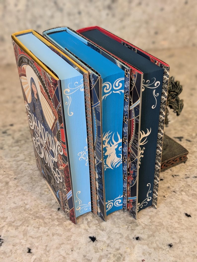 Puede incluir: Cinco libros de tapa dura con diferentes colores de lomo y dise&ntilde;os intrincados. Los lomos son rojo, amarillo, azul, azul y negro. Los libros tienen detalles dorados y patrones decorativos.
