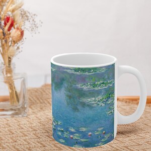 Puede incluir: Taza de cer&aacute;mica blanca con un estampado de nen&uacute;fares azul y verde. El estampado presenta un fondo azul con nen&uacute;fares y hojas verdes.