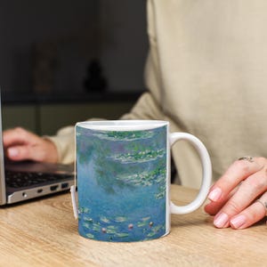 Puede incluir: Taza de cer&aacute;mica blanca con una imagen colorida de nen&uacute;fares y un cielo azul. La imagen es una pintura de nen&uacute;fares de Claude Monet.