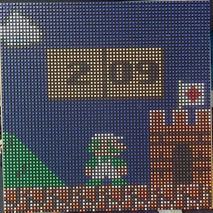 May include: A pixel art image of a video game character, a green and white figure, standing on a brown platform. The character is in front of a brown brick wall with a red and white flag on top. The background is a blue sky with a white cloud and a brown box with the word "EXIT" in white.