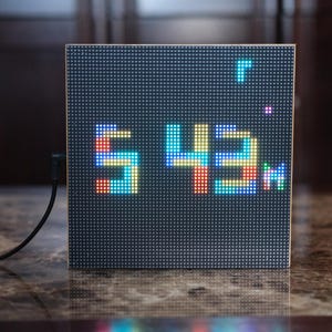 May include: A black LED display with a white frame showing the number "543" in a pixelated font. The display is connected to a black cable.