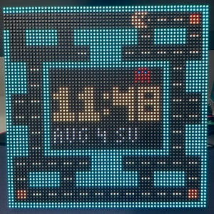 May include: A black and white LED display with a blue border shows the time 11:14. The display has a red and white pixelated image in the top right corner.