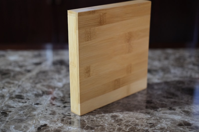 May include: A rectangular cutting board made of light brown bamboo. The board has a smooth surface and is made of multiple pieces of bamboo that are joined together.