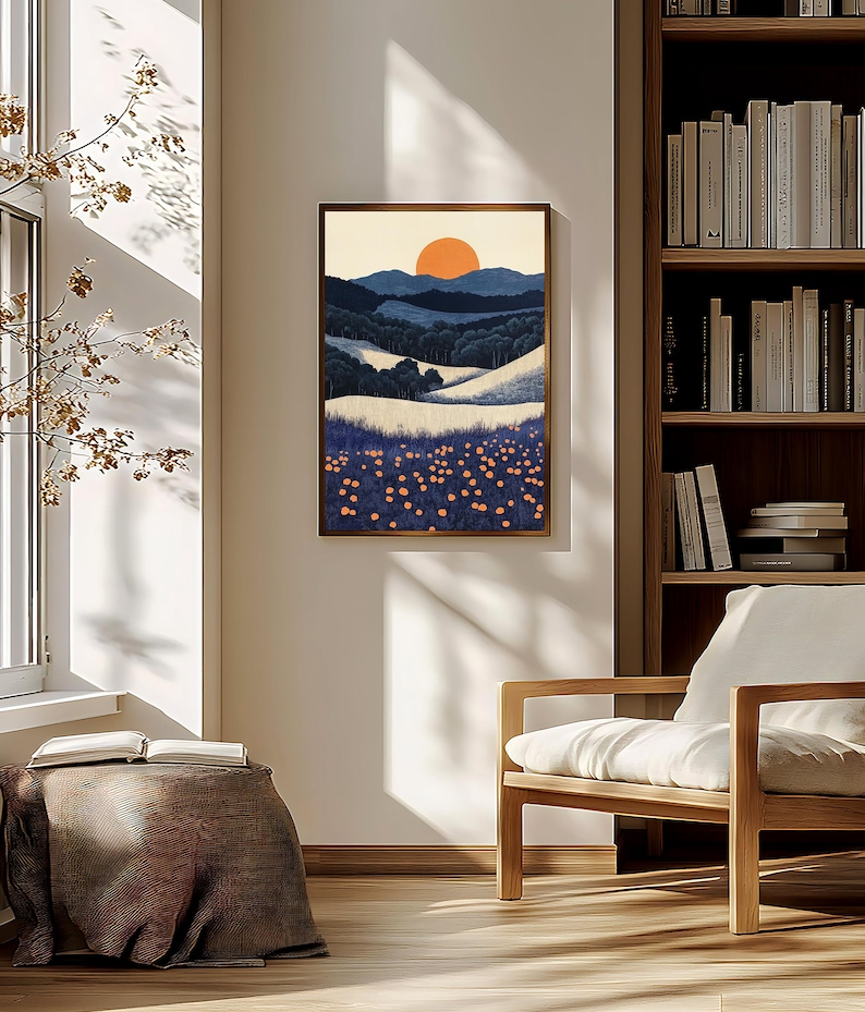 May include: A framed landscape art print depicting a sunset over rolling hills and a field of flowers. The artwork features a warm color palette with shades of orange, blue, and white. The print is displayed in a room with natural light.