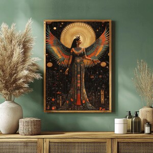 May include: A framed art print depicting a woman with large, colourful wings. The artwork has a dark background with gold and orange accents, and the woman is wearing a detailed, ornate dress. The print is displayed on a green wall.