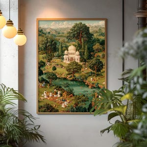 May include: A framed print depicts a serene landscape with a white domed building, a lake, and figures picnicking. Lush green trees and rolling hills fill the background. The artwork is encased in a gold-toned frame, creating a classic aesthetic.