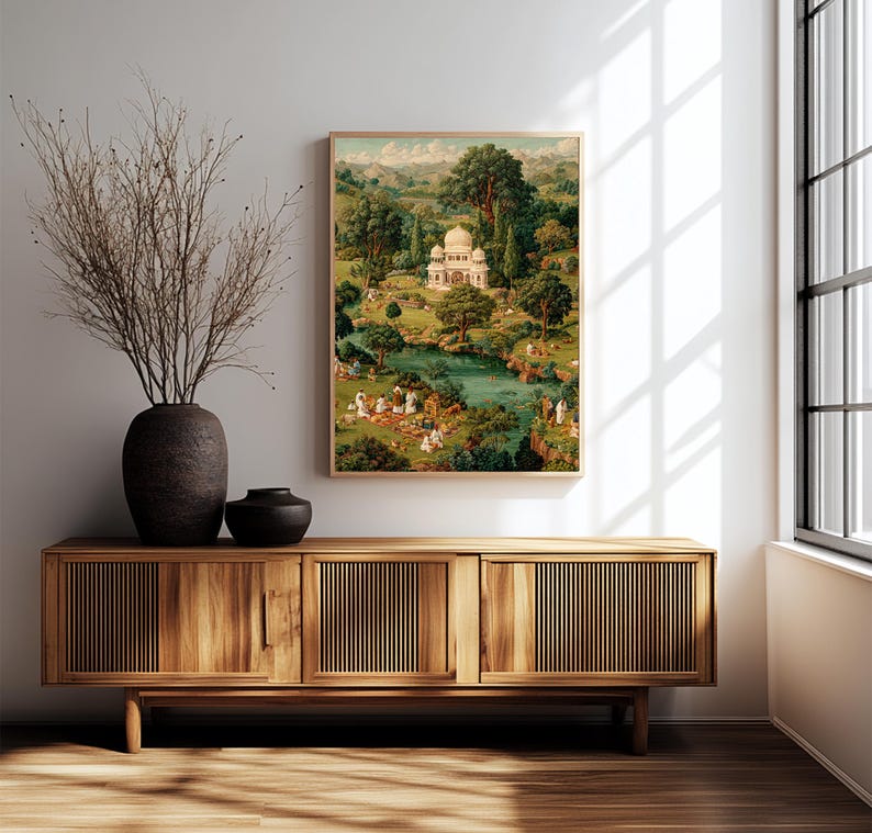 May include: A framed vintage print depicts a serene landscape with a white domed building, a river, and lush greenery. The artwork is displayed above a wooden cabinet with a dark vase and decorative branches.