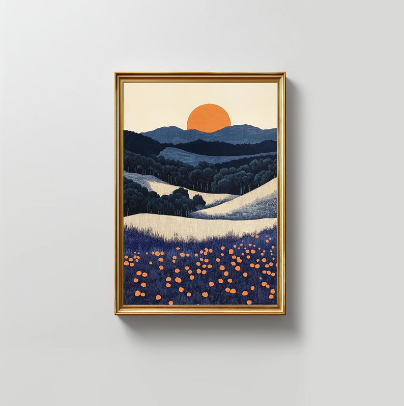 May include: Framed art print featuring a stylized landscape. The artwork depicts rolling hills, a forest, and a setting sun in shades of blue, white, and orange. The print is encased in a gold-colored frame.