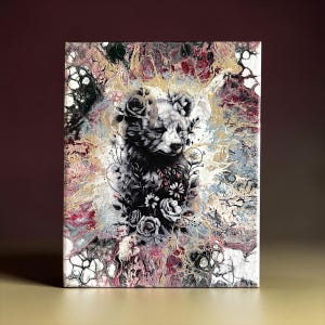 May include: A rectangular canvas painting featuring a central black and white illustration of a bear cub surrounded by floral elements. The background consists of an abstract fluid acrylic pour with marbled swirls of gold, deep red, and black paint.