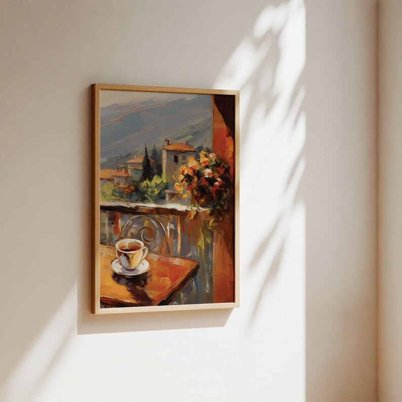 K&ouml;nnte beinhalten: Ein gerahmtes Gem&auml;lde eines Balkons mit Blick auf eine kleine Stadt, im Vordergrund ein Tisch mit einer Tasse Kaffee. Das Gem&auml;lde ist in warmen Farben gehalten, mit Braun-, Orange- und Gelbt&ouml;nen.