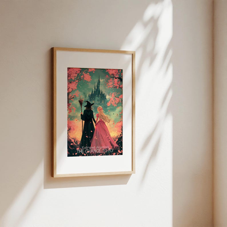 May include: A framed print of a fantasy illustration featuring two women walking away from a castle. The woman in the front is wearing a pink dress and the woman in the back is wearing a black dress and a witch's hat. The text "Everyone deserves the chance to fly" is at the bottom of the print.