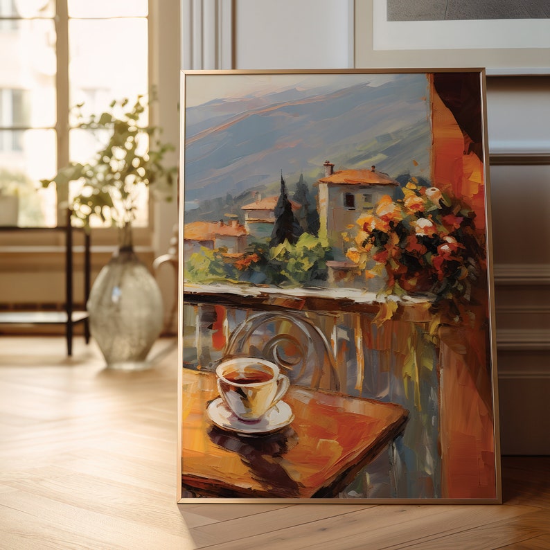 K&ouml;nnte beinhalten: Ein gerahmtes Gem&auml;lde einer farbenfrohen Landschaft mit einer Tasse Kaffee auf einem Tisch im Vordergrund. Die Landschaft zeigt ein kleines Dorf mit Geb&auml;uden und B&auml;umen und eine Bergkette im Hintergrund. Das Gem&auml;lde ist in einem goldenen Rahmen.