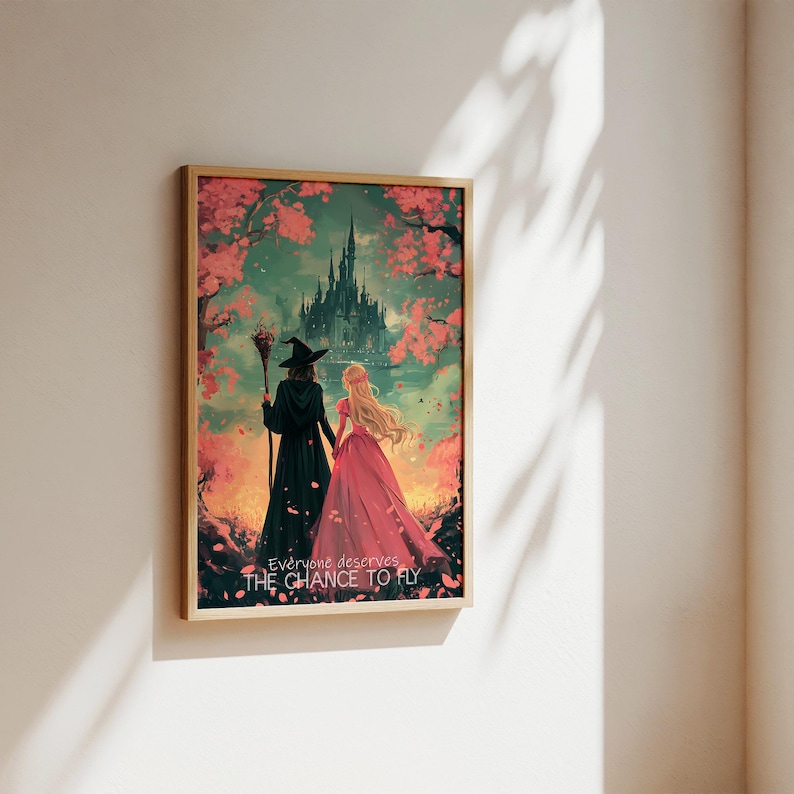 May include: A framed illustration of two women walking away from a dark castle. The woman in the front is wearing a pink dress and the woman in the back is wearing a black dress and a witch's hat. The background is a pink and green landscape with a quote that reads "Everyone deserves the chance to fly."