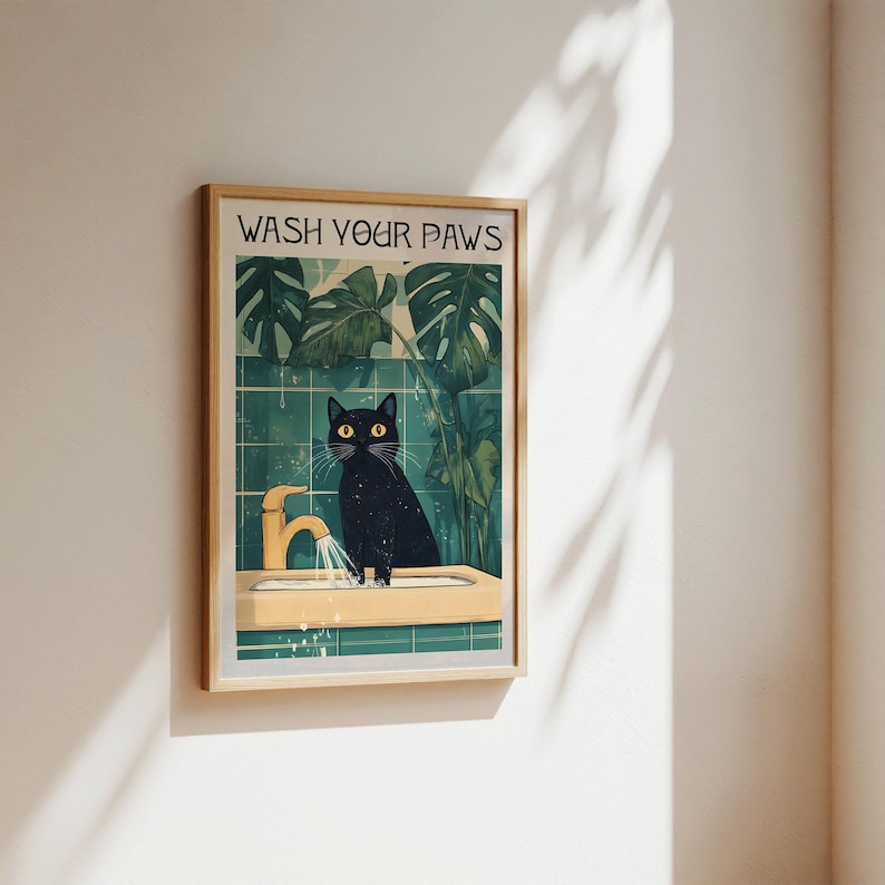 Puede incluir: Un gato negro con ojos amarillos se encuentra en un lavabo de ba&ntilde;o con un grifo dorado. El gato est&aacute; mirando a la c&aacute;mara. El lavabo es blanco con un salpicadero de azulejos verdes. El texto "WASH YOUR PAWS" est&aacute; escrito en letras negras sobre un fondo blanco en la parte superior de la imagen.