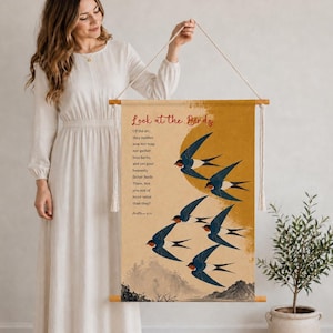 Könnte beinhalten: Ein vertikaler Wandbehang mit beigem Hintergrund, einem großen goldenen Kreis, einer Gruppe fliegender blauer und orangefarbener Schwalben sowie dem Text: Look at the Birds. Of the air; they neither sow nor reap nor gather into barns, and yet your heavenly father feeds Them. Are you not of more value than they? Matthew 6:26.