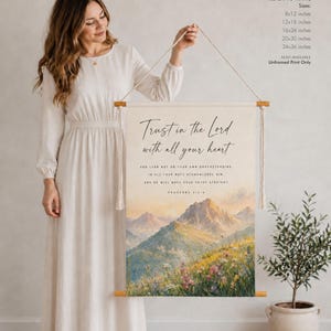 Könnte beinhalten: Ein rechteckiger Wandbehang aus Baumwolle mit einer Berglandschaft und Wildblumen am Fuß. Der Text lautet: Trust in the Lord with all your heart, and lean not on your own understanding; in all your ways acknowledge him, and he will make your paths straight. Proverbs 3:5-6.