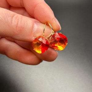 May include: A pair of gold earrings with large, faceted, orange and red gemstones.