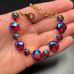 Peut inclure: Un bracelet doré orné de cristaux carrés et ronds irisés multicolores. Les cristaux présentent des nuances de rouge, de bleu et de violet. Le bracelet est doté d'un fermoir mousqueton et d'une chaîne d'extension.