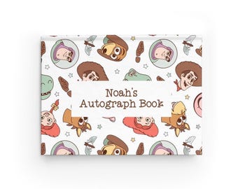 Könnte beinhalten: Ein rechteckiges Autogrammbuch mit weißem Einband, das ein wiederkehrendes Muster aus Zeichentrickfiguren und kleinen Sternen zeigt. Ein zentrales weißes Etikett trägt den braunen Text Noah's Autograph Book.
