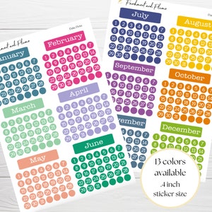 May include: A set of 12 colourful monthly calendar stickers with white numbers and text. Each sticker is 10 cm in diameter and features a different colour and design. The stickers are ideal for planning and organising your schedule.