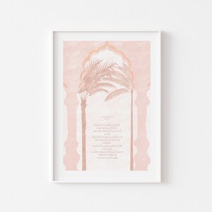 Op de afbeelding: Een roze en witte printbare kunstprint met een Arabisch kalligrafieontwerp en een silhouet van palmbomen in een boog.