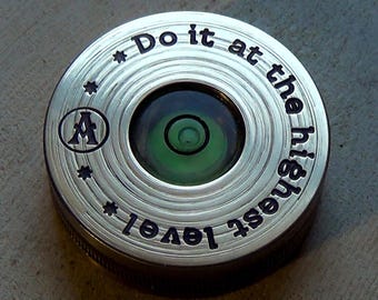 May include: A silver circular level with a green bubble level and the text "Do it at the highest level" engraved around the edge.
