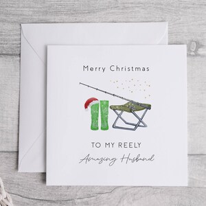 May include: A white Christmas card with a green fishing boot wearing a Santa hat, a fishing rod, and a folding chair. The card says "Merry Christmas to my Reely Amazing Husband".