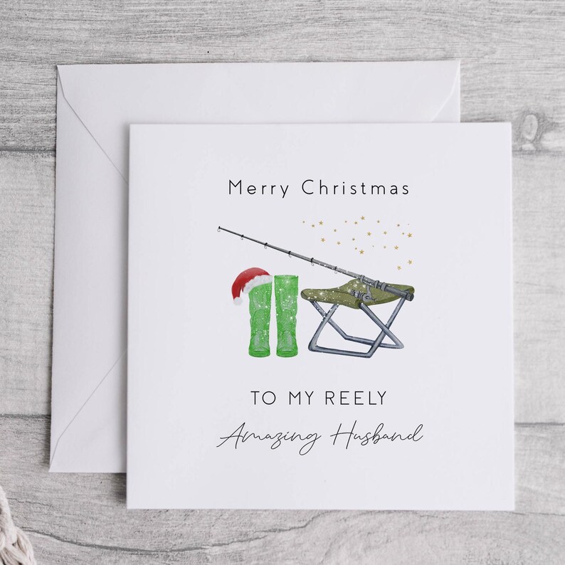 May include: A white Christmas card with a green fishing boot wearing a Santa hat, a fishing rod, and a folding chair. The card says "Merry Christmas to my Reely Amazing Husband".