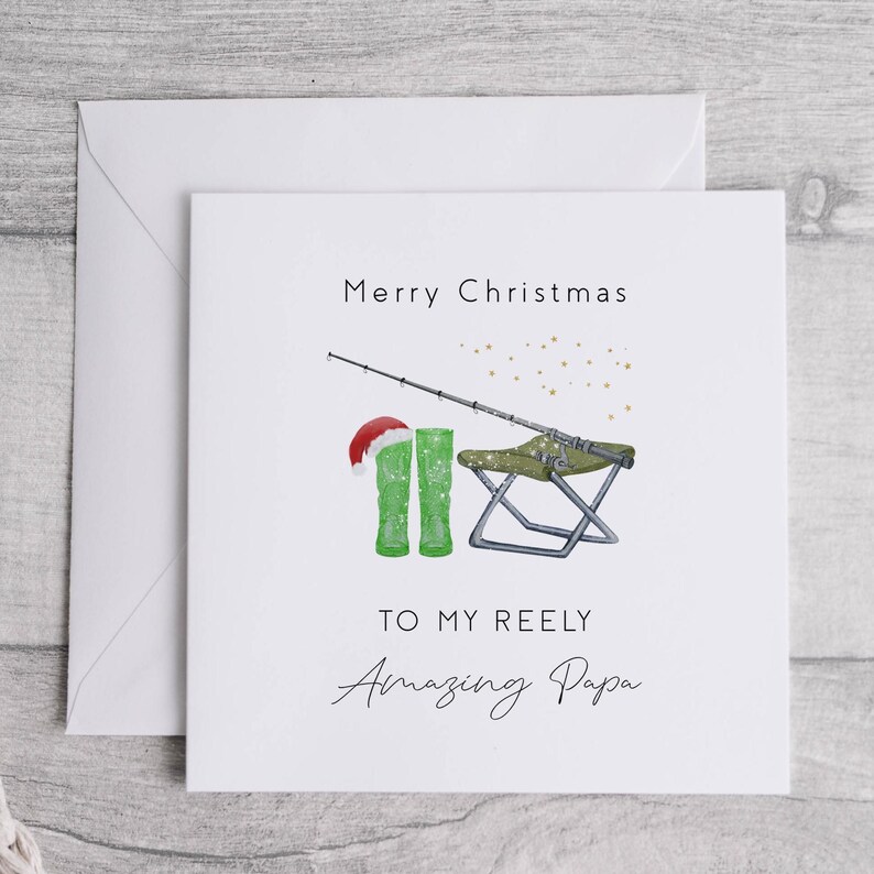 May include: A white Christmas card with a fishing rod, green boots, a folding chair, and the text "Merry Christmas To My Reely Amazing Papa".
