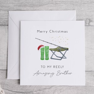 May include: A white Christmas card with a green fishing boot, a fishing rod, and a folding chair. The card says "Merry Christmas" and "To my Reely Amazing Brother".