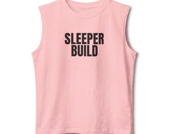 Puede incluir: Una camiseta sin mangas de color rosa claro con el texto "SLEEPER BUILD" impreso en letras mayúsculas negras y negritas en el centro del pecho. La prenda tiene un cuello redondo, un corte estándar con sisas acabadas y un dobladillo recto.