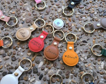 May include: Assortment of leather keychains with personalised engravings. The keychains feature different colours, including brown, red, orange, and white. Some keychains have names engraved on them, while others have coordinates or a heart design.