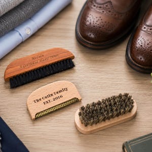 以下が含まれることがあります： 毛のついた3つの木製ブラシ。1つのブラシは黒い毛で、Mr. Colin A Gentleman Always Shinesと刻印されています。別のブラシは明るい色の毛で、The Cotin Family EST. 2016と刻印されています。3つ目のブラシは暗い色の毛です。