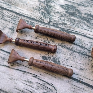 May include: Three brown back scratchers with handles textured to resemble wood grain. Each handle features engraved text: I GOT YOUR BACK DAD! LOVE, PENNY, I'VE GOT YOUR BACK, and Daddy we have your back! The scratchers have a fan-shaped head.