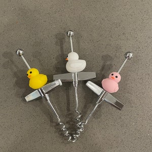May include: Three silver corkscrews with different coloured rubber ducky handles. The ducks are yellow, white, and pink.