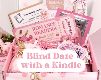 May include: A pink gift box labelled "Blind Date with a Kindle" is filled with pink paper. Inside are various items, including a "Romance Readers Book Club" ticket, lip balm, and other pink accessories. The box has a polka dot pattern.