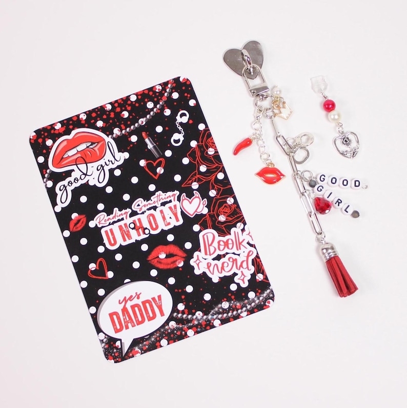 Kindle accessories flat lay featuring watercolor kindle insert for clear case paired with charm keychain, dust plug charm, and kindle stickers. Styled with cozy socks, cocoa, and tea to represent a blind date with a kindle mystery box experience designed for readers decorating their kindle paperwhite, kindle oasis, kindle scribe, or ereader case with aesthetic kindle decorations and booklover gifts.