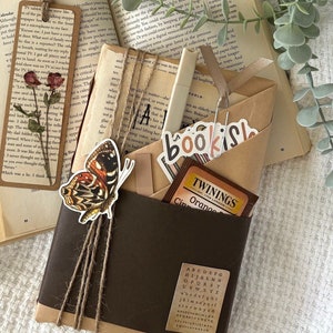 May include: A brown paper-wrapped package with twine, a butterfly sticker, and a tea bag. The package is decorated with stickers that say "bookish" and "TWNINGS Orange Cinnamon".