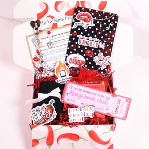 Blind Date with a Kindle. Decorative kindle insert placed inside a clear kindle case with hanging kindle charm keychain and dust plug charm attached to the charging port. Styled with kindle stickers and cozy accessories, this kindle mystery box gift is designed for readers who enjoy customizing their kindle paperwhite, kindle oasis, or kindle scribe with aesthetic kindle inserts, kindle skins, and personalized kindle decorations.