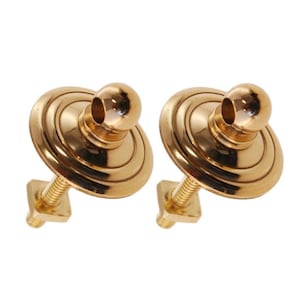 May include: Two gold-toned metal curtain tiebacks with a round knob and a flat base. Each tieback has a screw for mounting.
