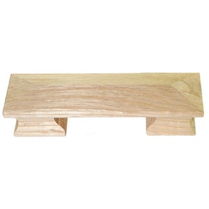 May include: A wooden drawer pull with a rectangular shape and two square-shaped supports on either end. The pull is made of light-colored wood with a natural grain pattern.