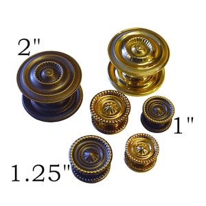 May include: Assortment of five gold-toned metal door knobs in various sizes, including 1 inch, 1.25 inches, and 2 inches.