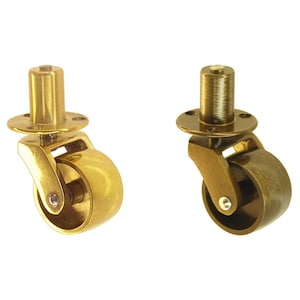May include: Two brass swivel casters with a polished finish. The casters have a round wheel and a threaded stem for mounting.
