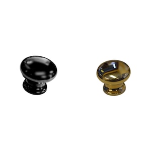 May include: Two cabinet knobs, one black and one gold. The knobs are round and have a raised center.