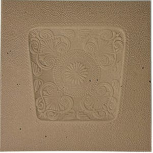 May include: A square, tan leather coaster with a detailed, embossed floral and scroll design. The central motif is a circular pattern with a flower-like center, surrounded by swirling leaves and curls. The coaster has a textured border.