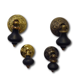 May include: Four antique-style cabinet knobs with a black wooden base and a gold metal top. The knobs have a decorative floral design.