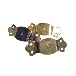 May include: Three antique-style metal drawer pulls. Two are gold-toned and one is silver-toned. Each pull has a decorative, ornate design with a rounded shape and four holes for attaching to a drawer.