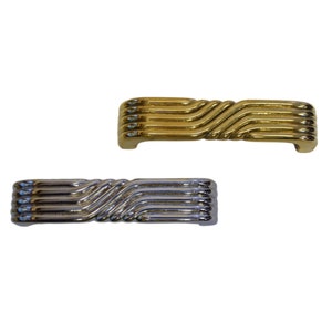 May include: Two cabinet pulls, one gold and one silver, with a wavy, ribbed design.