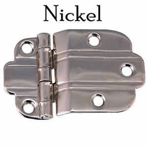 May include: Nickel plated cabinet hinge with a decorative design. The hinge has three visible leaves and four screw holes.